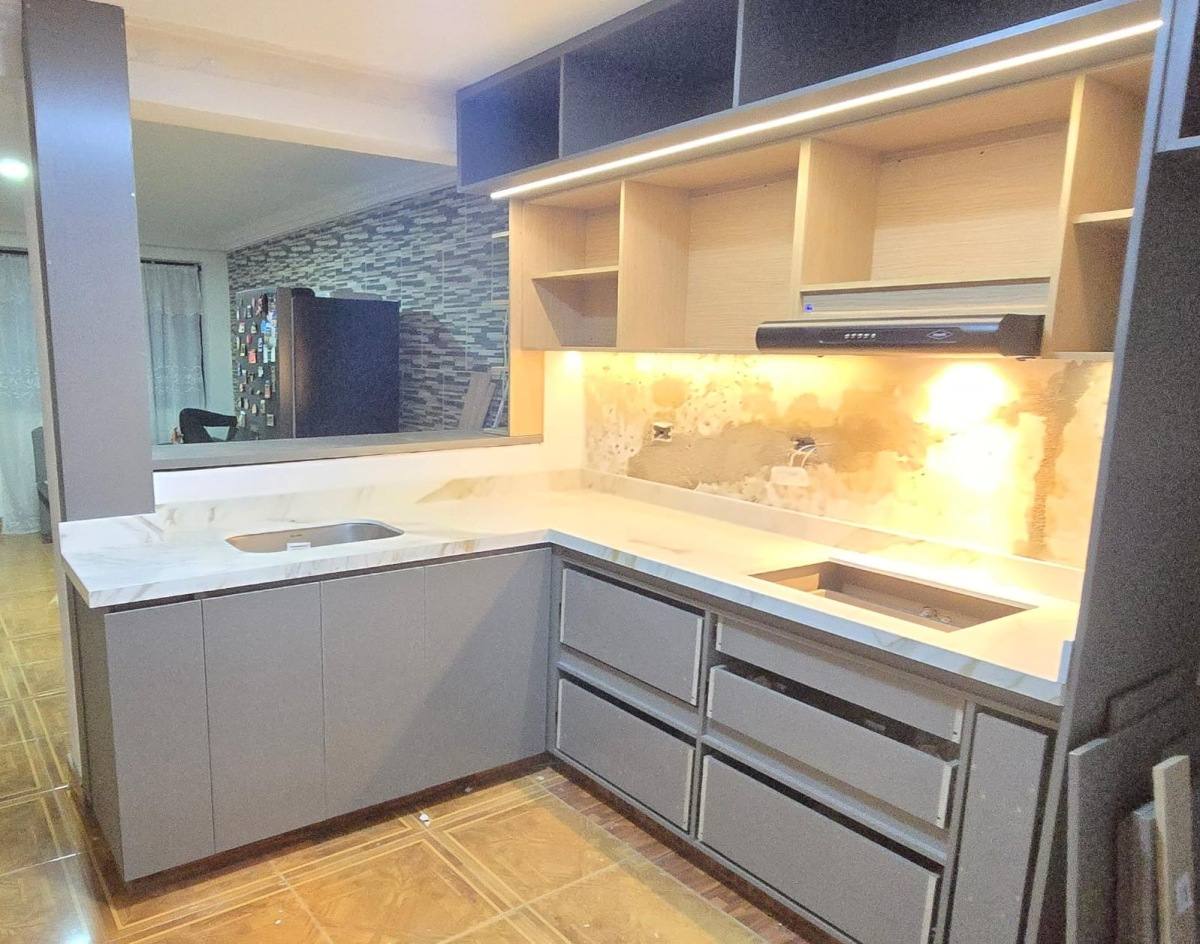 Cocina con mesón y salpicadero veteado dorado, muebles grises y luz led