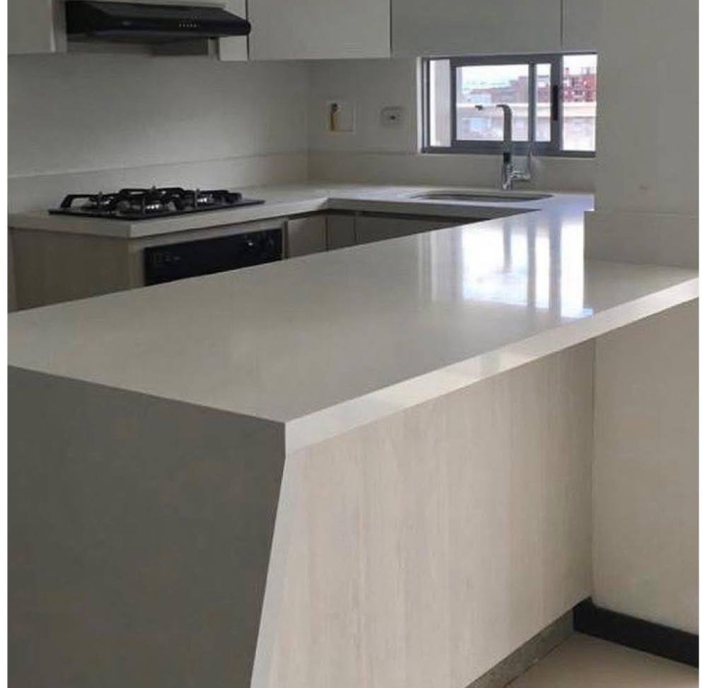 Cocina en U con península en mesón de cuarzo claro, estufa empotrada y poceta con grifería