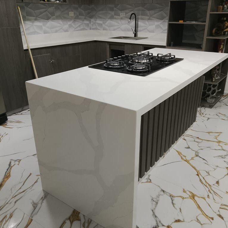 Isla de cocina en cuarzo blanco con cascada lateral y estufa empotrada